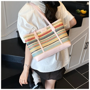 Detail shot of multi-color striped woven tote bag with pink leather trim and logo plate