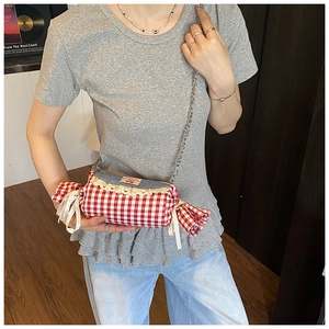 Detail of candy-shaped plaid crossbody bag with denim flap and lace trim on model