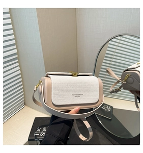 Detail of minimalist beige crossbody bag with woven texture flap and gold rotating clasp