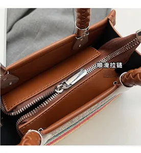 Detail view of a brown tote bag featuring a smooth metal zipper and rainbow woven texture