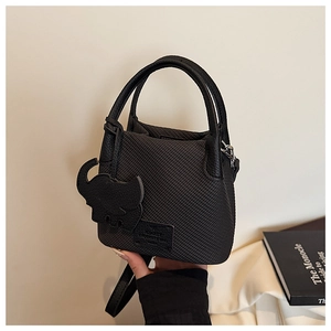 Detail of black woven leather handbag with elephant charm and cylindrical top handle