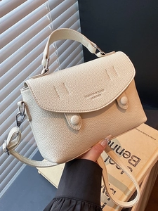 Elegant cream lychee leather handbag with flap closure and adjustable shoulder strap