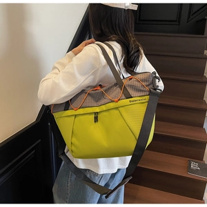 Detail of checkered crossbody bag with neon accents and orange bungee cord detail