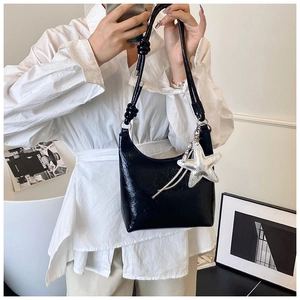 Détail du sac hobo noir brillant avec breloque étoile de mer et texture plissée