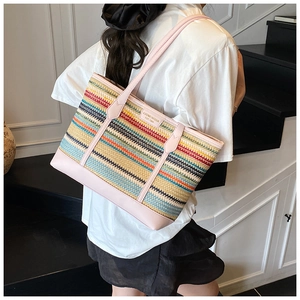 Lifestyle shot showing the large colorful striped woven straw tote bag on a model shoulder