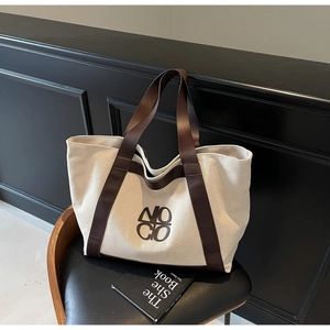 Detail of a minimalist canvas tote bag in off-white with premium dark brown leather straps