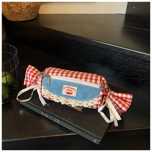 Detail of candy-shaped red gingham and denim bag with lace and white ribbon bows
