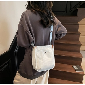 Dettaglio di borsa a tracolla minimalista in tela crema con fibbia in metallo sul modello