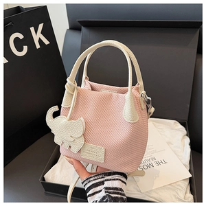 Pink woven bucket bag with leather brand tag, white handles and cute elephant charm detail