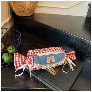 Close-up of candy-shaped plaid handbag with denim lace detail on a vintage book