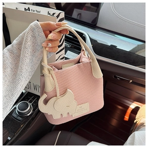 Detailed texture of pink woven bucket bag with leather elephant charm and litchi grain handle