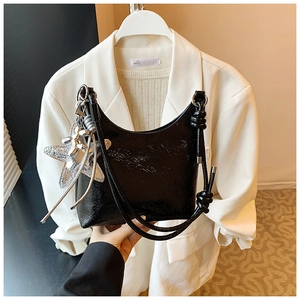 Détail du sac seau noir en cuir verni froissé avec breloque étoile et bandoulière nouée