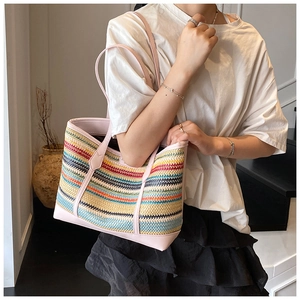 Detailed macro of multi-colored striped woven straw tote bag with pink leather shoulder strap