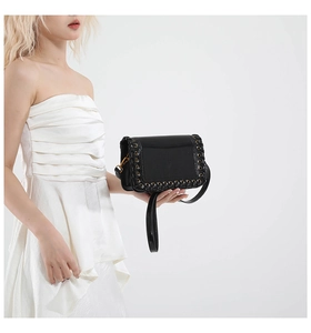 Close-up of black woven leather edges and metal eyelets on a punk style square bag