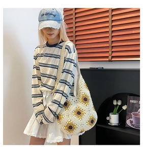 Detailed close-up of handmade white knit hobo bag with yellow sunflower floral pattern