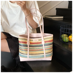 Detail of colorful striped straw tote bag with pink leather trim and metal logo brand tag