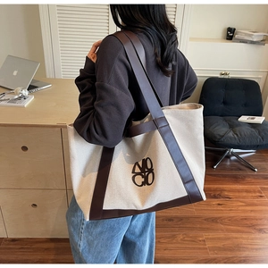 Side view of large canvas tote bag with dark brown leather straps in a home office setting