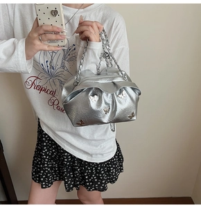 Close-up of silver bucket bag with metallic butterfly accents and thick chain strap