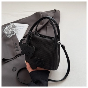 Detail of black lychee grain bucket bag with elephant charm and slender shoulder strap