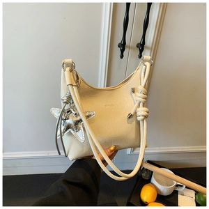 Gros plan d'un sac seau en cuir beige texturé avec pendentif étoile et bandoulière nouée