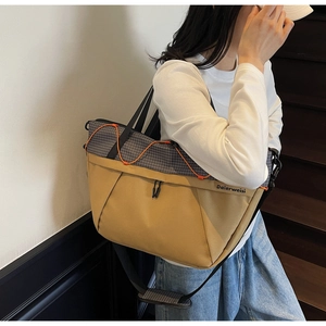 Detail of large sports tote bag featuring khaki and grey patchwork with orange bungee cord