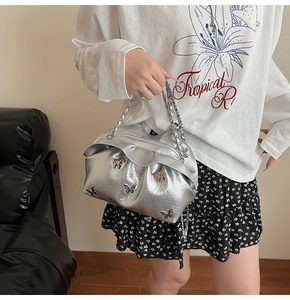 Close-up of silver pleated bucket bag with metallic butterfly accents and chain strap