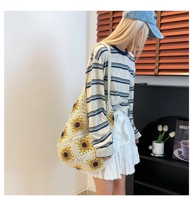 Detail of hand-woven crochet tote bag with sunflower patterns worn by a model