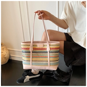 Detail of multi-color striped straw tote bag with pink leather handles and brand nameplate