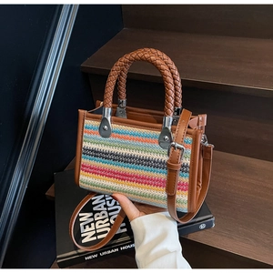 Detail of colorful striped woven handbag with brown leather handles and silver hardware