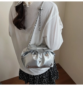 Detailed view of silver pleated bucket bag with butterfly charms and metal chain strap