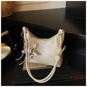 Détail du sac seau crème avec pendentif étoile et bandoulière à nœud élégante