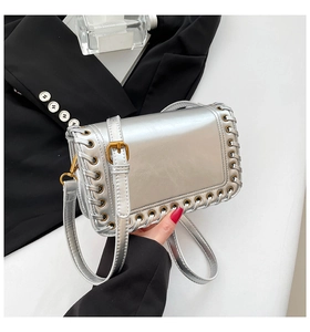 Detail of silver metallic leather bag with woven edges and gold hardware on a suit