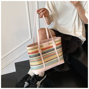 Detail of colorful striped straw tote bag with pink leather handles and brand logo