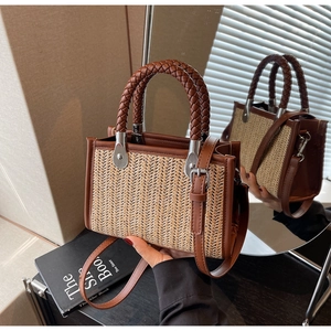 Detail of woven straw handbag with brown leather handles and adjustable shoulder strap