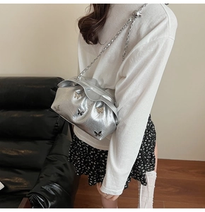 Detail view of silver pleated bucket bag with butterfly accents and metallic ball chain