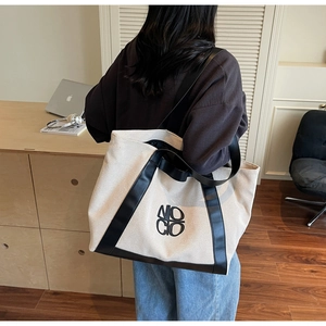 Detail of minimalist canvas tote bag with black leather trim worn in home office setting