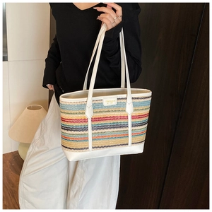 Detail of colorful striped woven tote bag with white leather handles and gold logo emblem