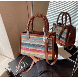 Detail of colorful striped woven handbag with brown leather handles and silver hardware