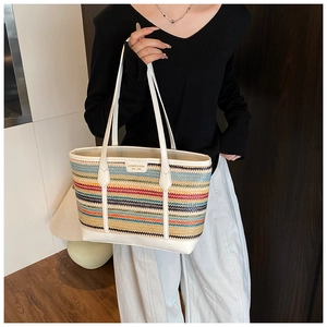 Detail of colorful striped woven tote bag with white leather handles and brand tag