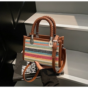 Close-up of colorful striped woven tote bag with brown leather straps on a book