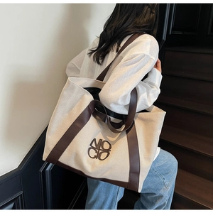 Lifestyle shot of large canvas tote bag with brown leather trim carried by a model