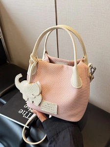 Pink woven bucket bag with beige leather trim and a cute elephant charm accessory