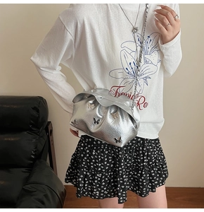 Detailed macro view of silver metallic pleated cloud bag with butterfly accents and chain