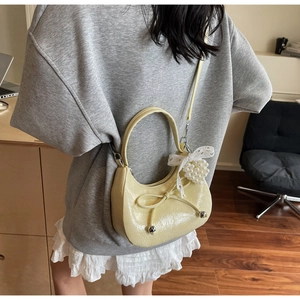 Détail du sac croissant jaune avec nœud décoratif et pendentif cœur en perles