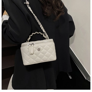 Détail du sac seau blanc matelassé avec logo fleur argenté et poignée en chaîne