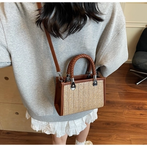 Detail of straw woven bag with brown leather handles and adjustable shoulder strap