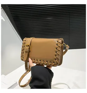 Detail of caramel glossy leather crossbody bag with distinctive braided edge craftsmanship
