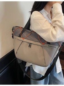 Large beige and grey plaid tote bag with orange drawstrings worn by a model