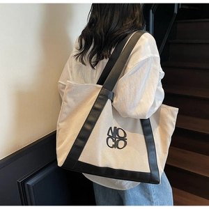 Lifestyle shot of large canvas tote bag with black leather straps and NO CO logo