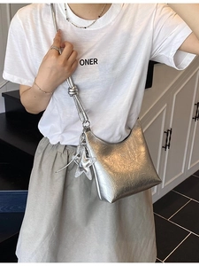 Sac seau argenté froissé avec pendentif étoile présenté dans un décor moderne chic